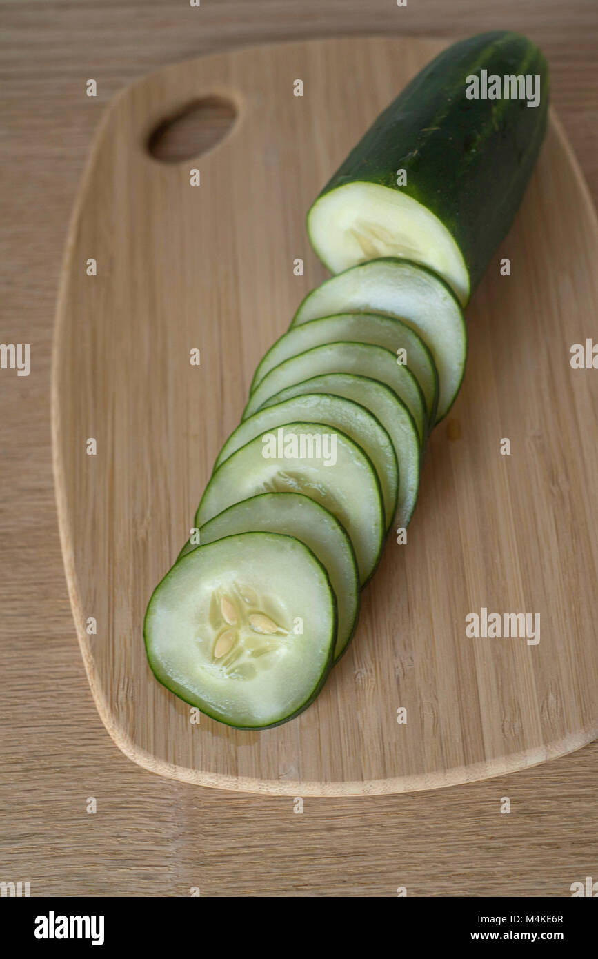 Overhead View of Half-Sliced Cucumber on a Wooden Counter Ready for Meal Prep Stock Photo