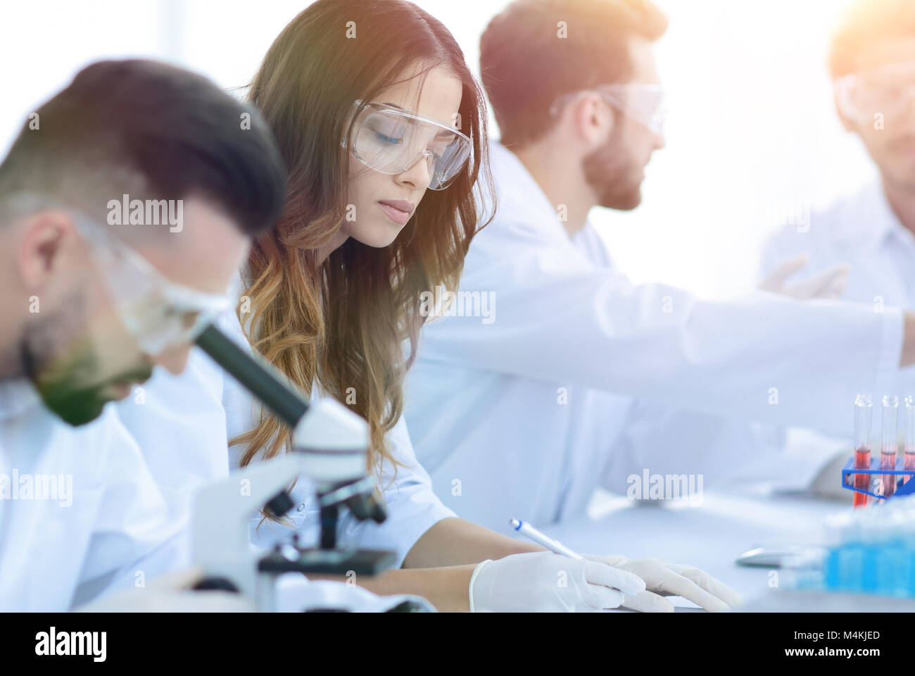 promising scientist looking in a microscope sitting in the lab. Stock Photo