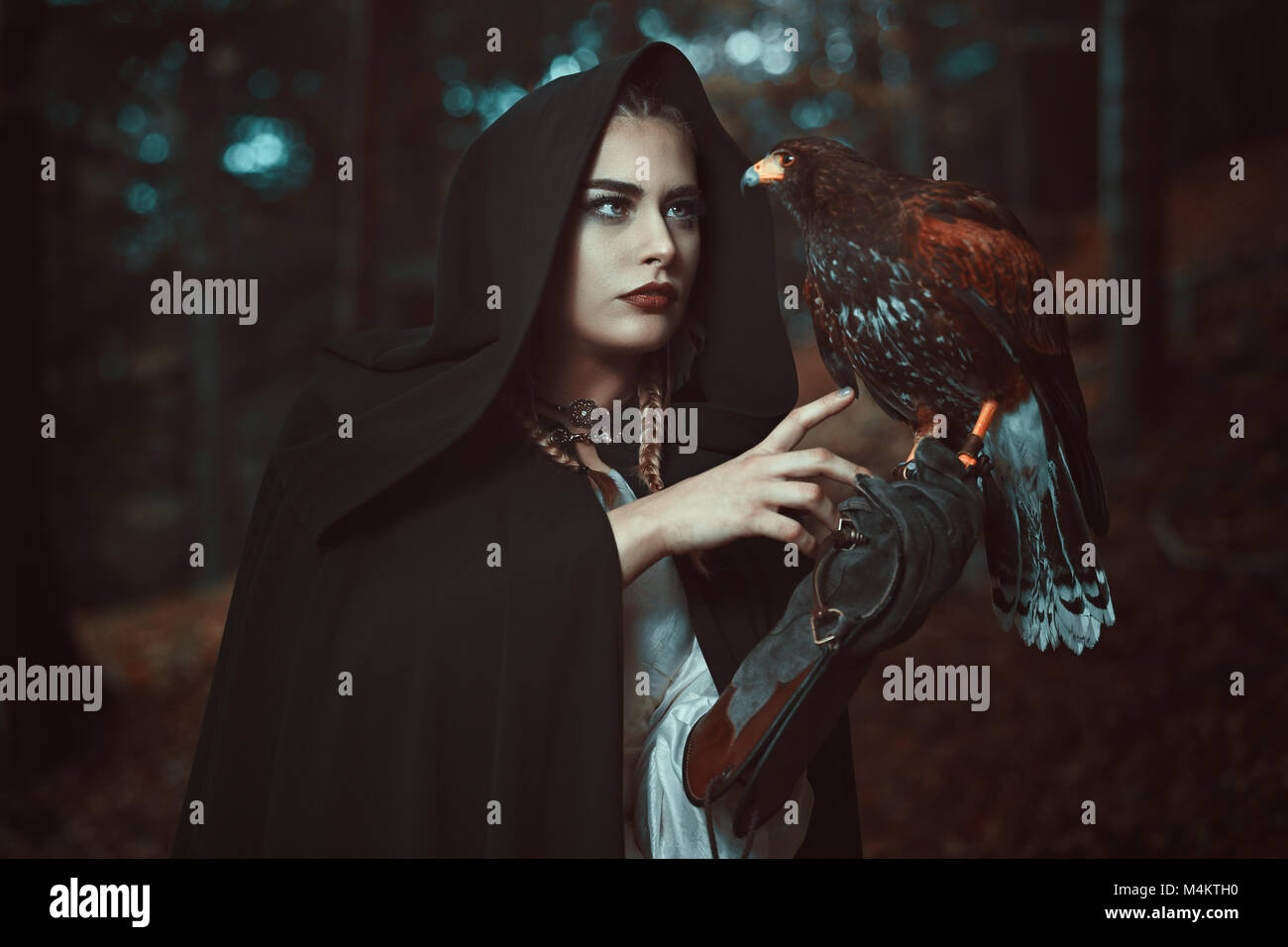 Magician woman with hawk familiar. Forest shot Stock Photo