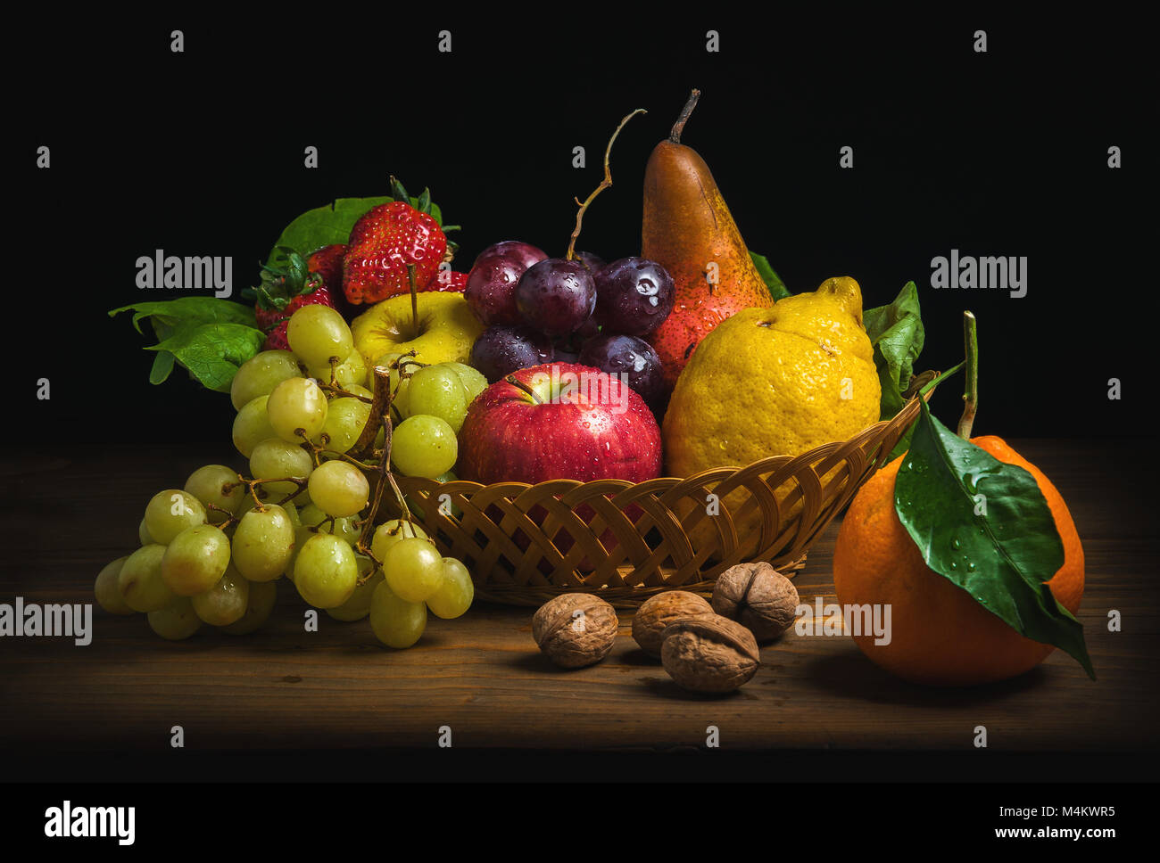 wicker basket with autumnal fruits in black background. Stock Photo