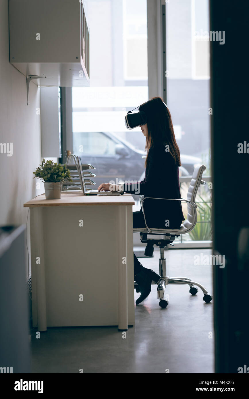 Executive working on laptop while using virtual reality headset Stock Photo