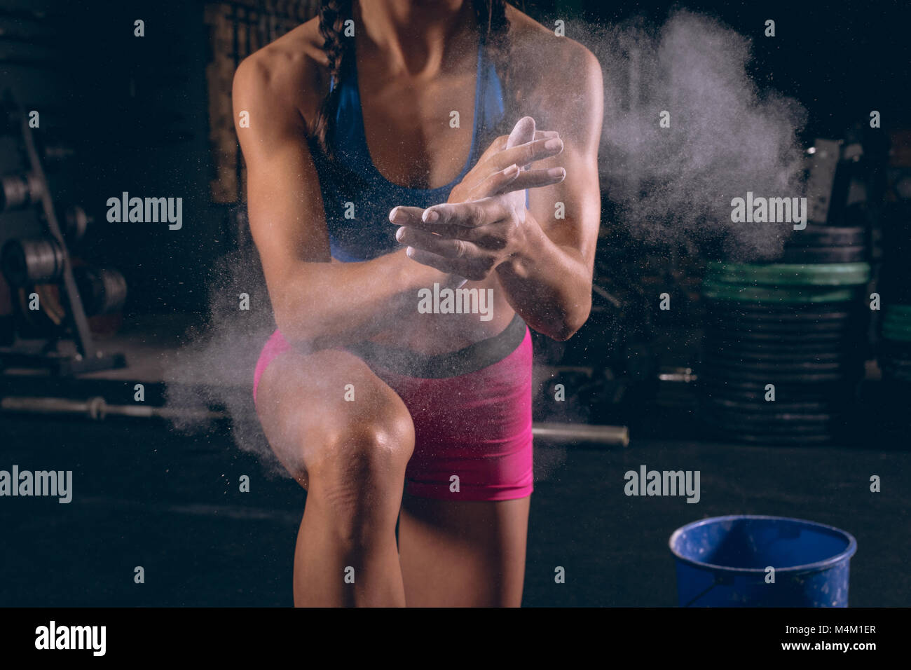 Fit woman dusting her hands with chalk powder in the gym Stock Photo