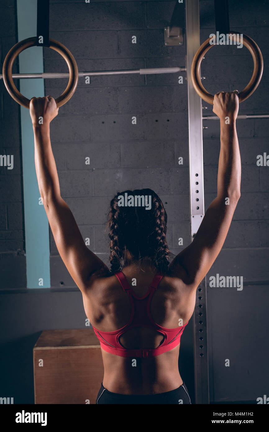 Fit woman exercising with gymnastic rings in the gym Stock Photo