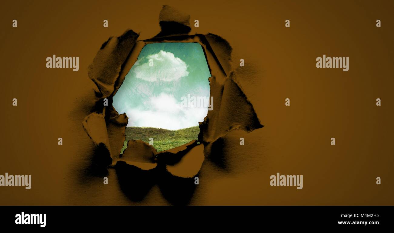 Bue sky and green field through surreal paper hole Stock Photo