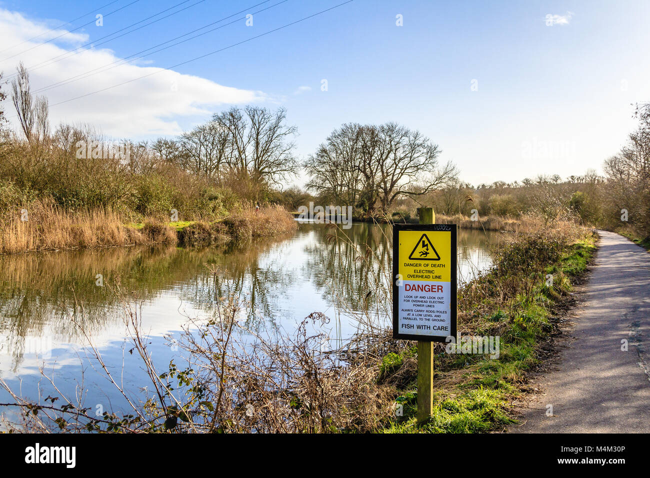 Warning sign beside the River Exe informing recreational fishers of the dangers of overhead power lines. Stock Photo