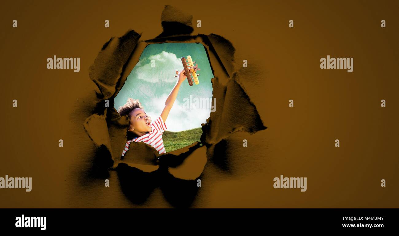 Boy playing with toy plane through surreal paper hole Stock Photo