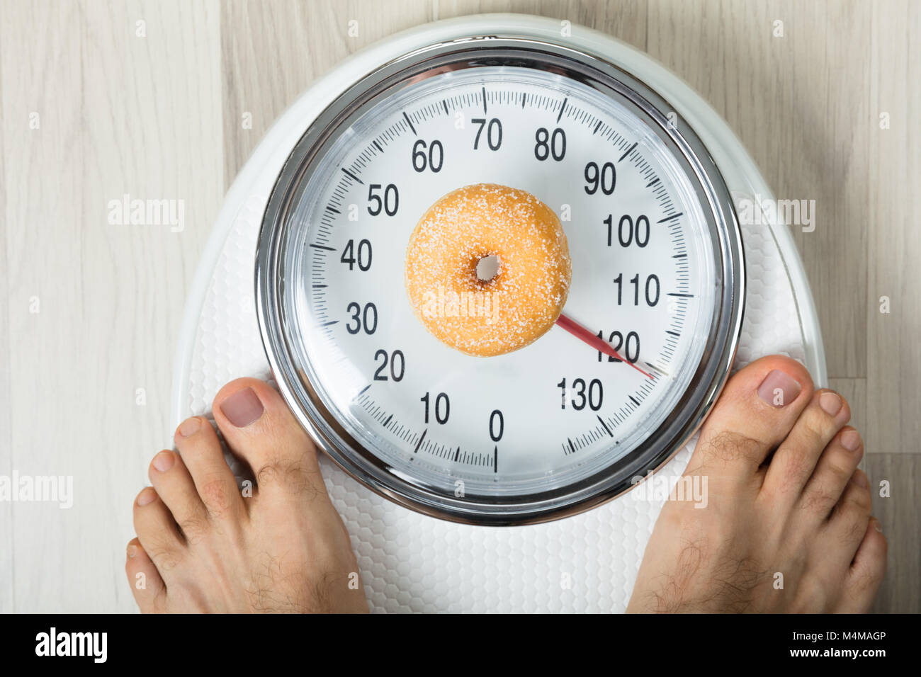 Close-up Of A Person Measuring Weight With Donut On Weighing Scale Stock Photo