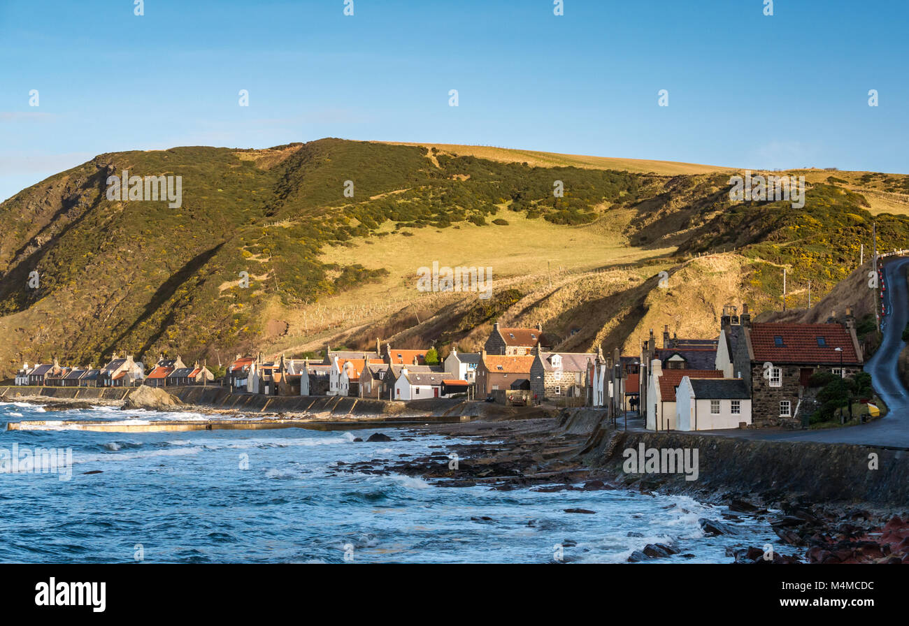 View of small picturesque seaside village Crovie, Aberdeenshire, Scotland, UK, with gable end old cottages on shore front and steep winding road Stock Photo