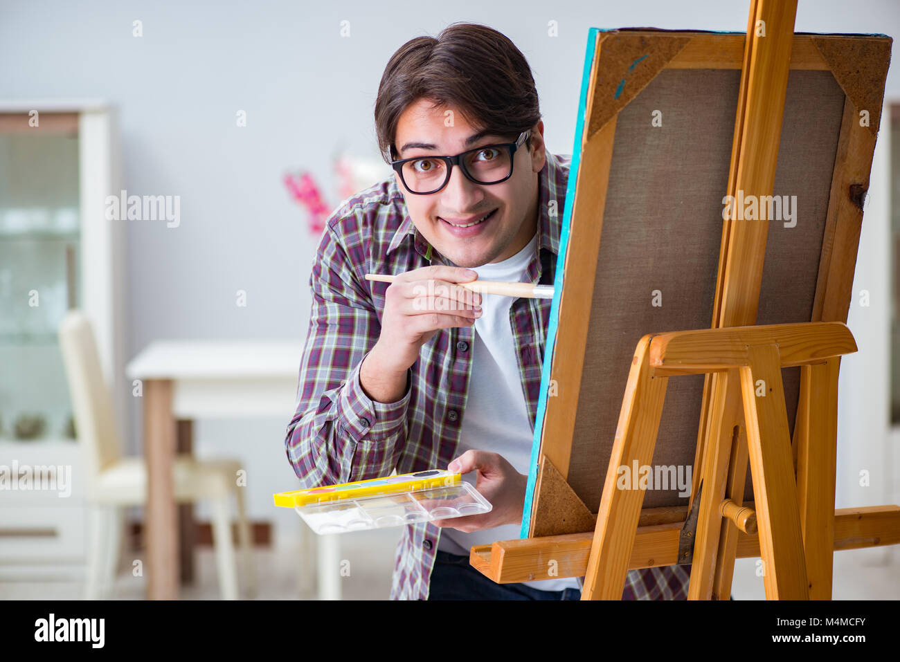 Young male artist drawing pictures in bright studio Stock Photo - Alamy