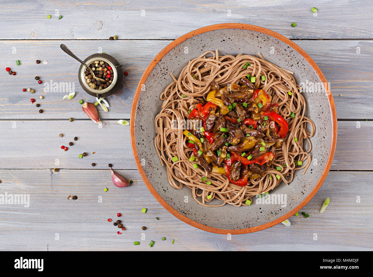 Stir fry from chicken hearts, paprika, onions and buckwheat noodles