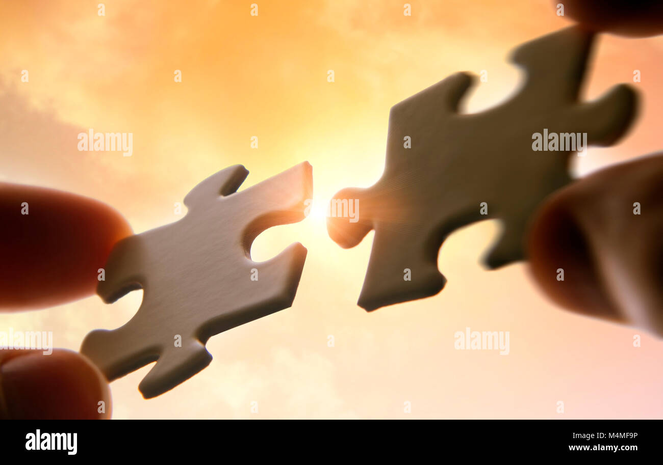 Hands putting puzzle pieces together on sky background with sunlight