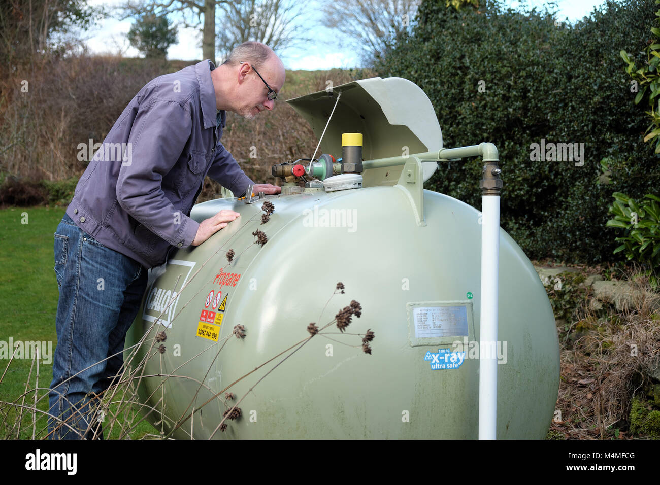 Calor gas male customer reading the capacity meter gauge in a rural UK setting Stock Photo