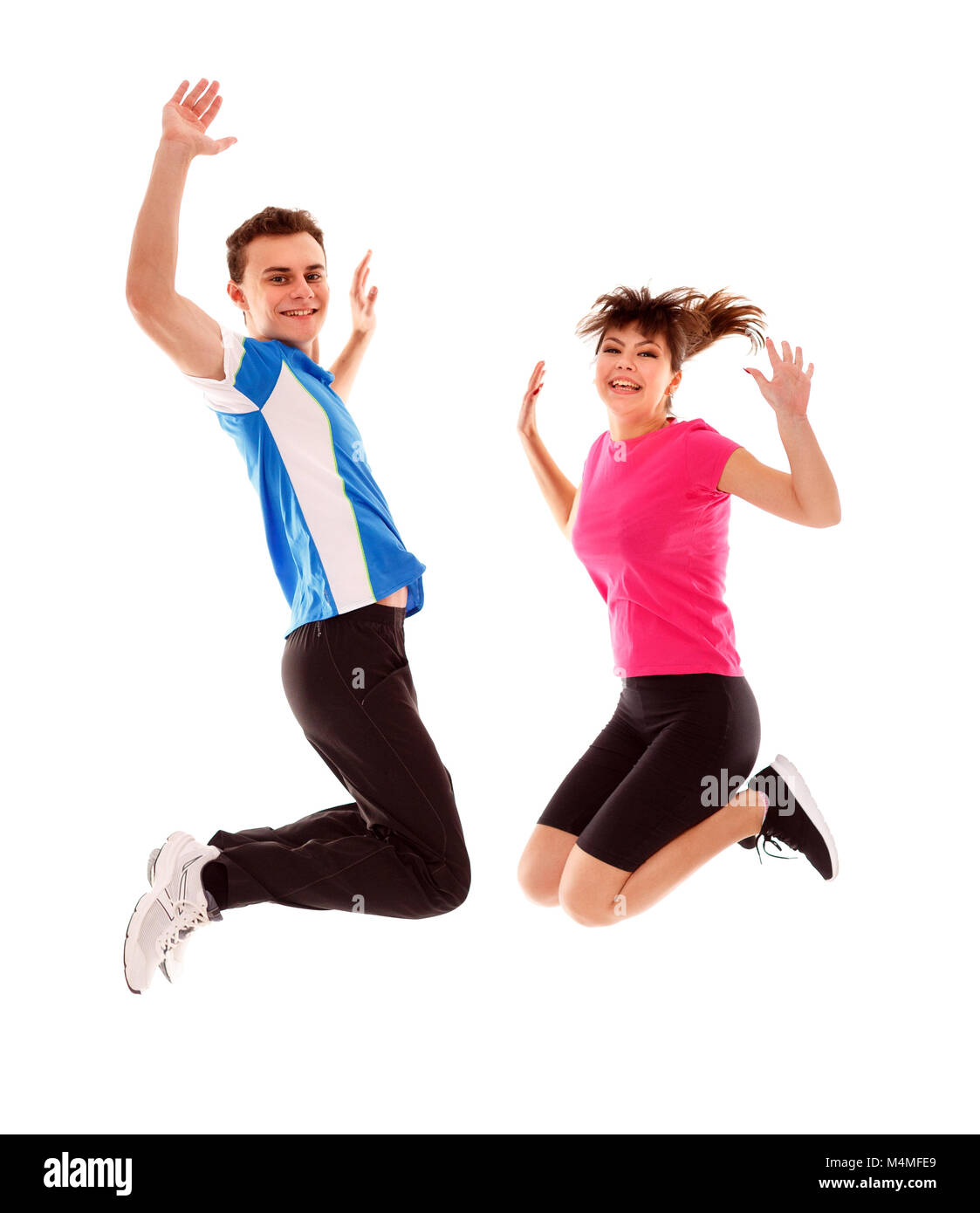 Boy and girl jumping for joy in track suits over white background Stock Photo