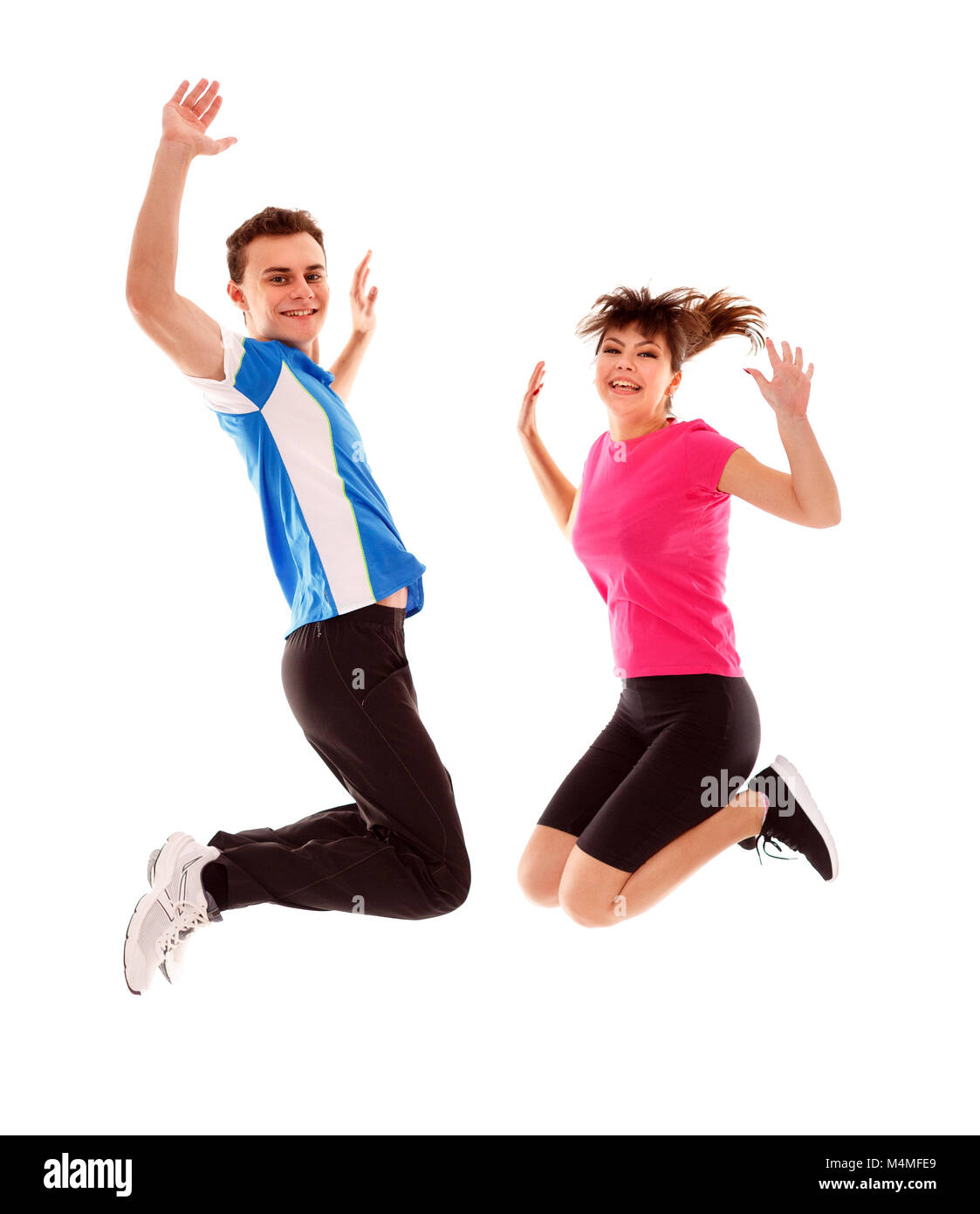 Boy and girl jumping for joy in track suits over white background Stock ...