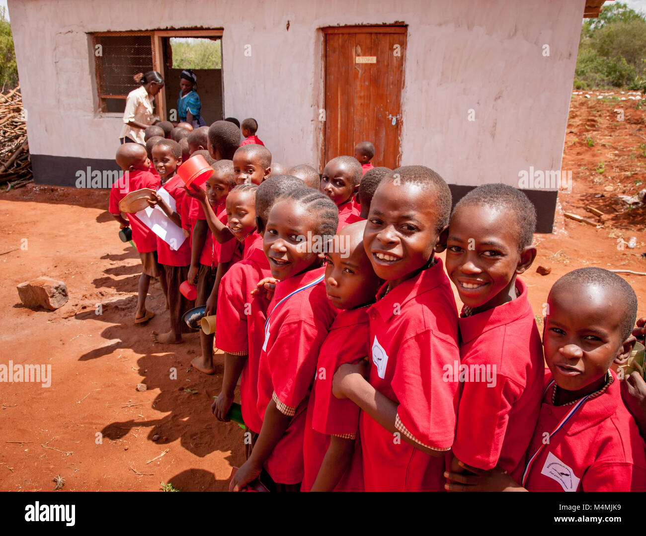 Children queueing for a lunchtime stew made with beans maize and onions at Kileva Primary School near Voi in Southern Kenya Stock Photo