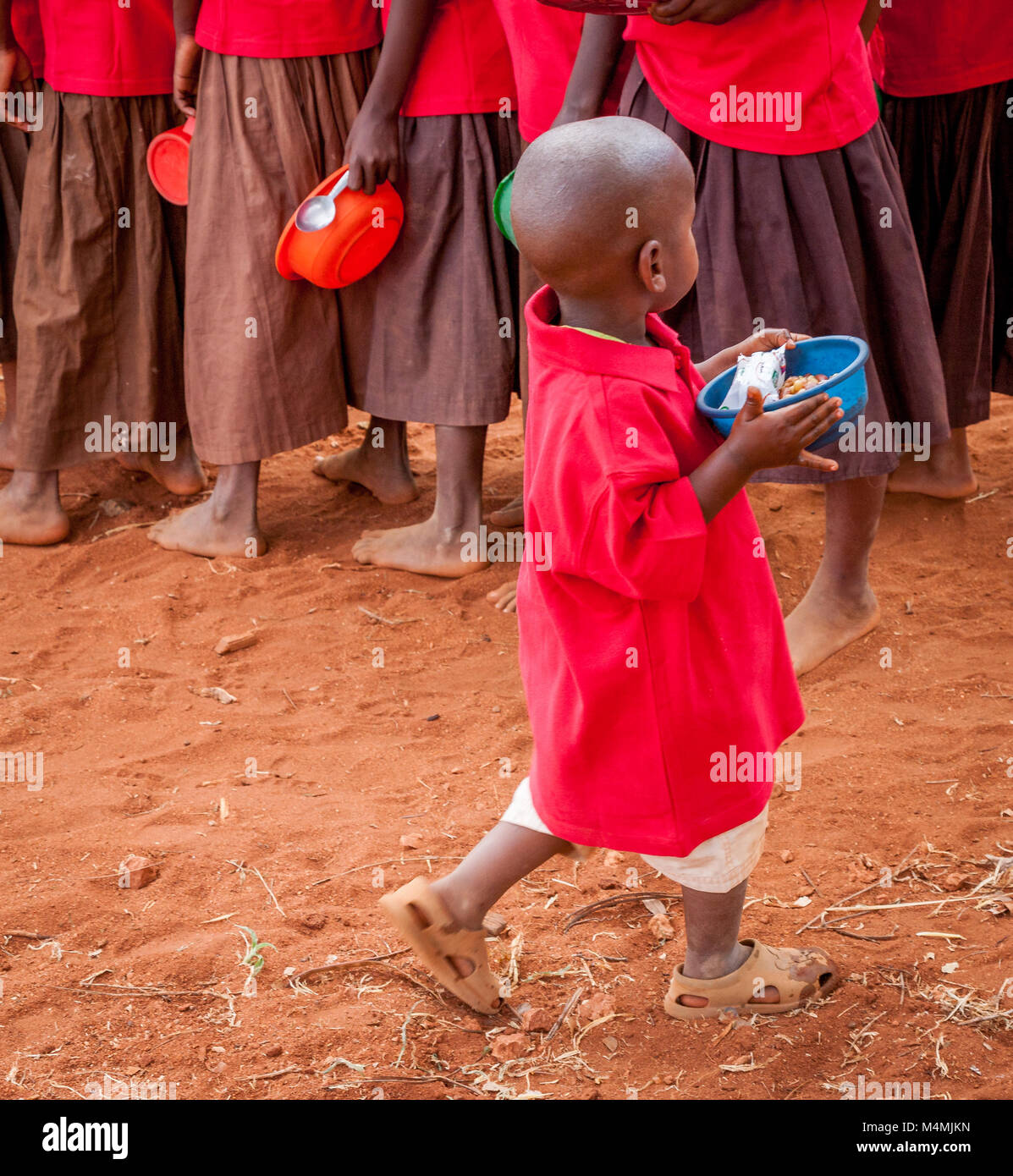Children queueing for a lunchtime stew made with beans maize and onions at Kileva Primary School near Voi in Southern Kenya Stock Photo