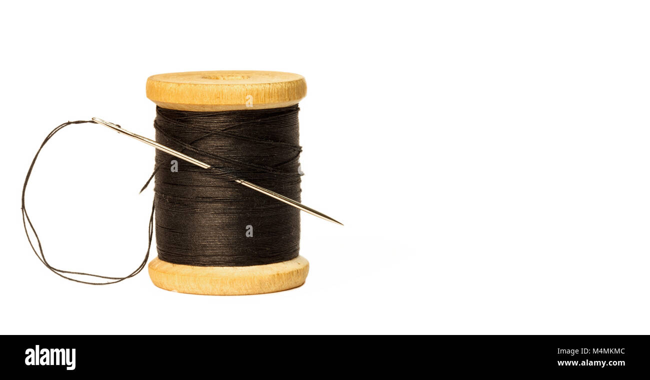 sewing needle with black thread stuck in wooden spool with black