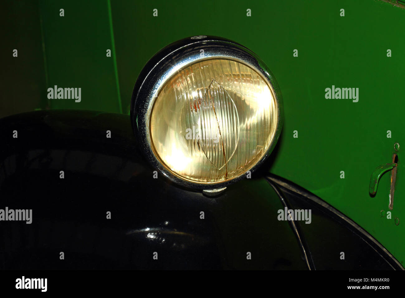 Old vintage car headlight on a green vehicle Stock Photo