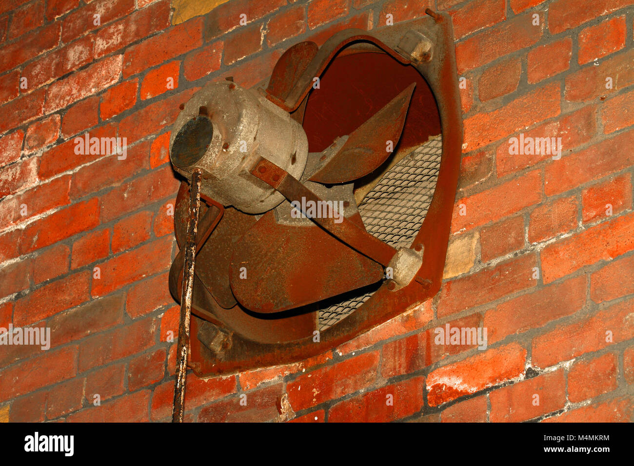 Old rusty metal factory fan set in a wall Stock Photo
