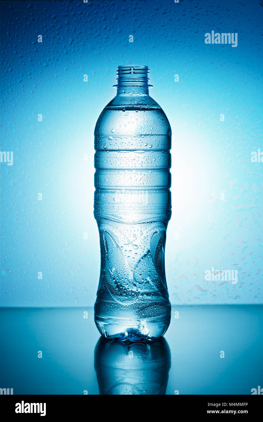 Blue plastic bottle with water drops on a blue background Stock Photo