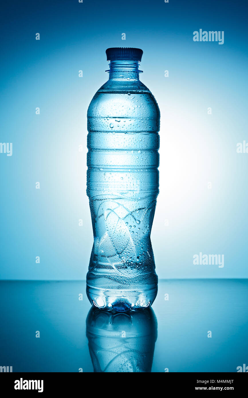 Blue plastic bottle with water drops on a blue background Stock Photo
