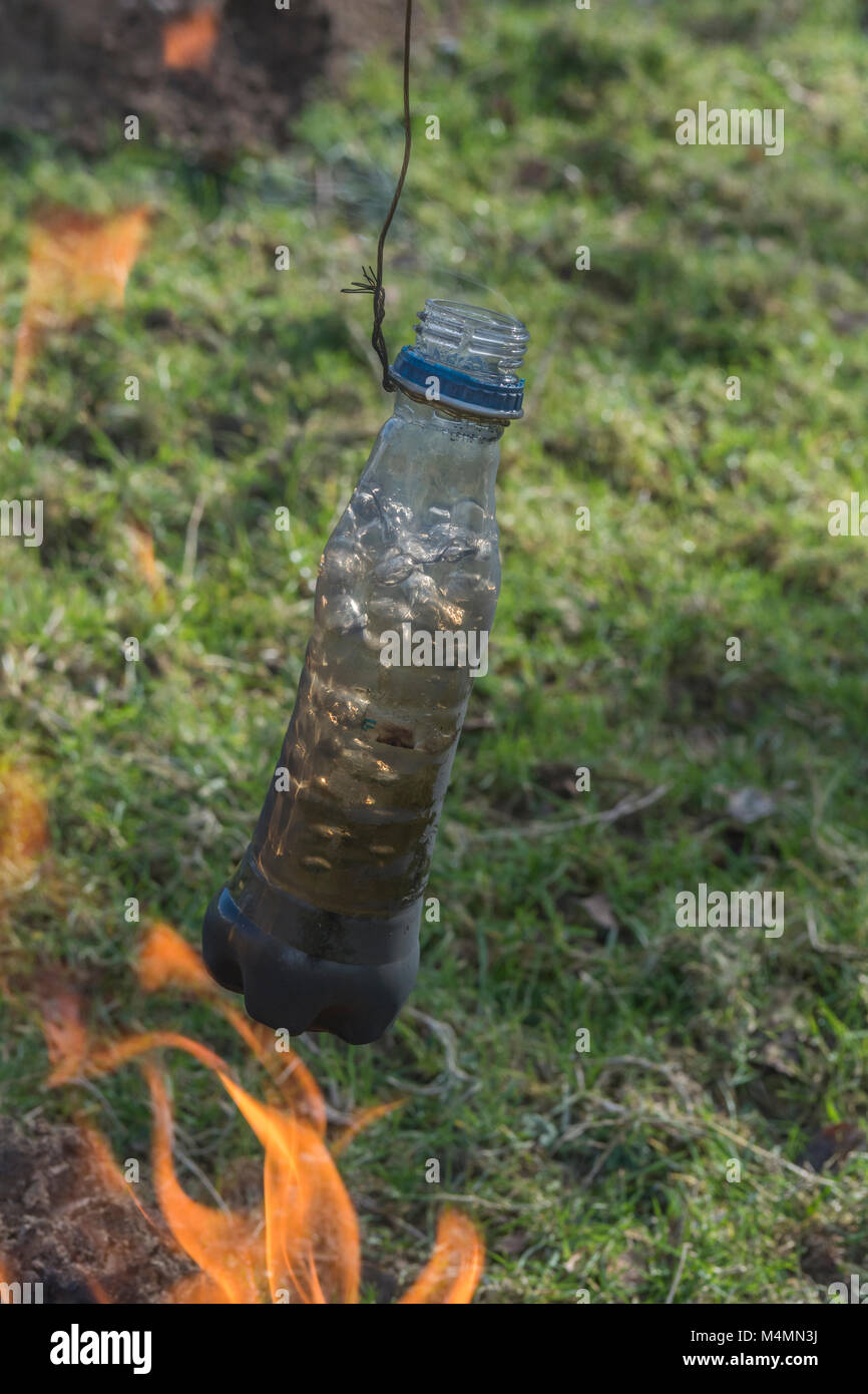 Survival skills / Überlebensfähigkeiten - boiling dirty / foul water in a plastic bottle to make it potable. ONLY to be done for survival - see NOTES. Stock Photo