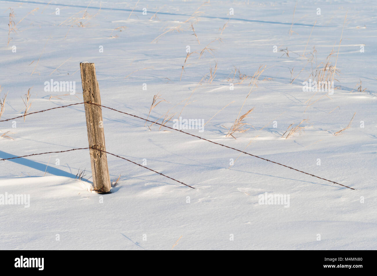 Old barbed wire fence buried in snow on the prairies Stock Photo