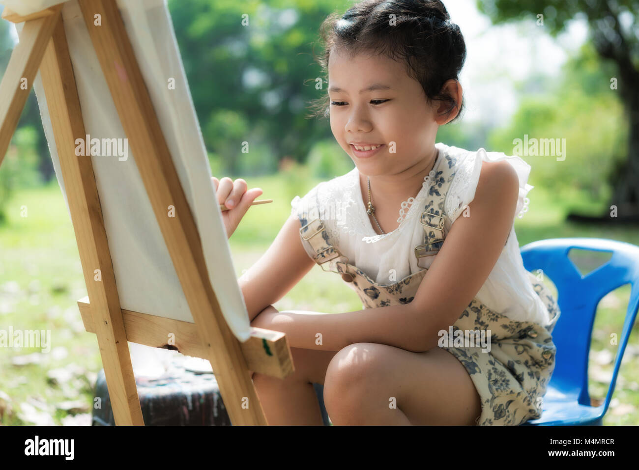 Asian children cute or kid girl painting water color on  paper and nature meadow at garden or public park for fun and preschool education on holiday r Stock Photo