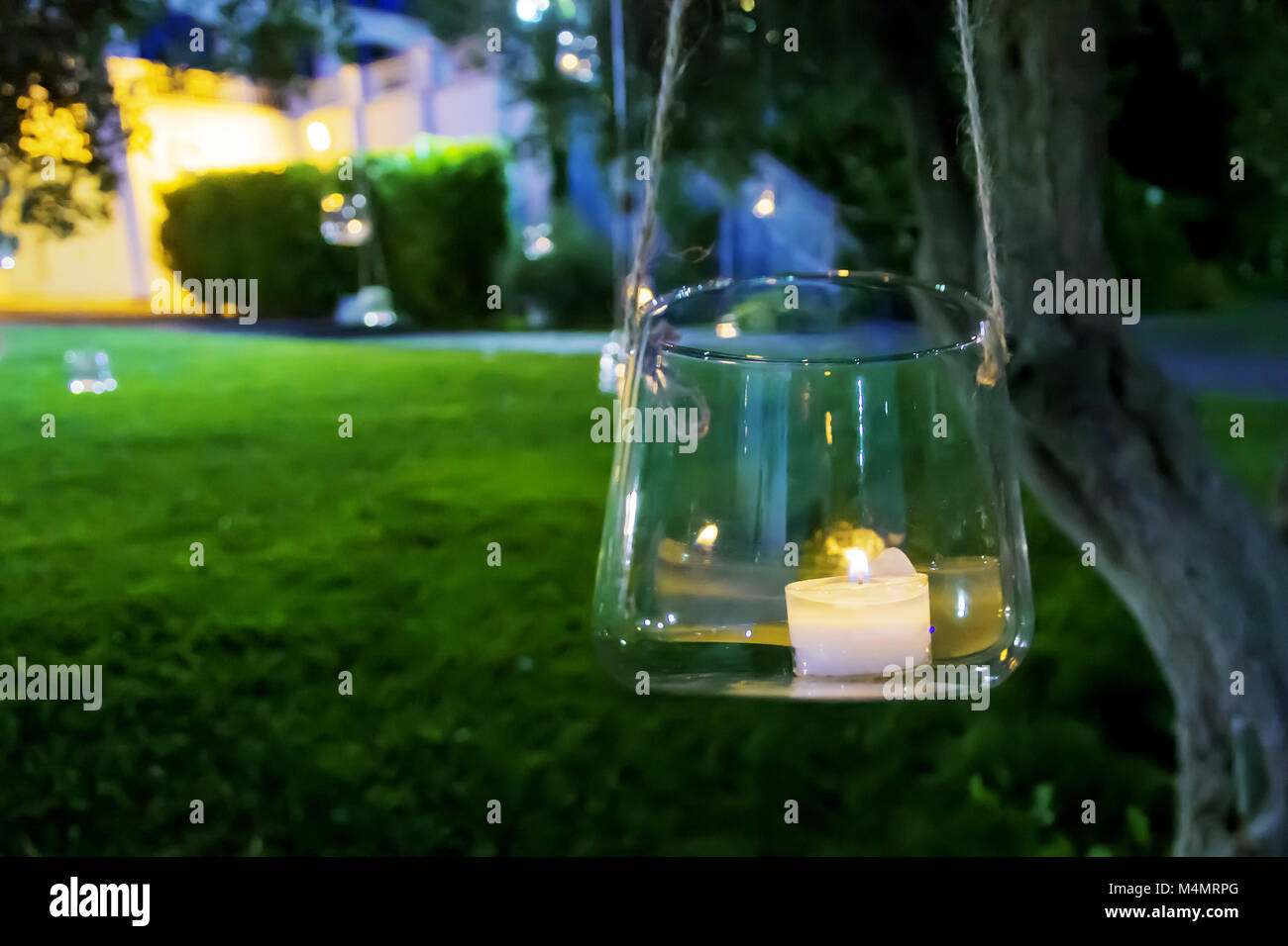 candle in a glass hanging from a tree Stock Photo Alamy