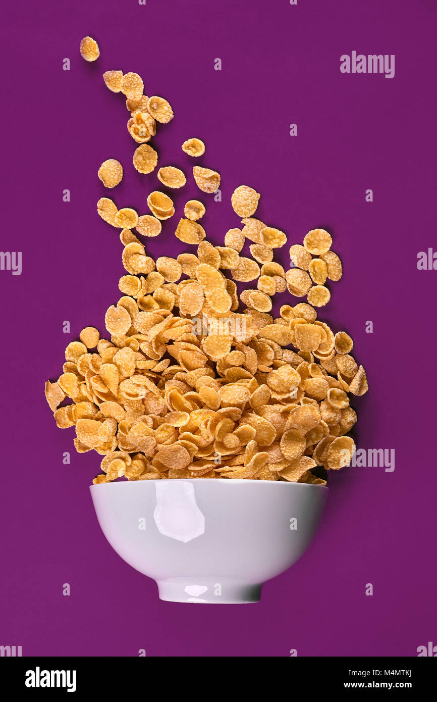 Bowl with cornflakes on the colorful background. Purple background, top