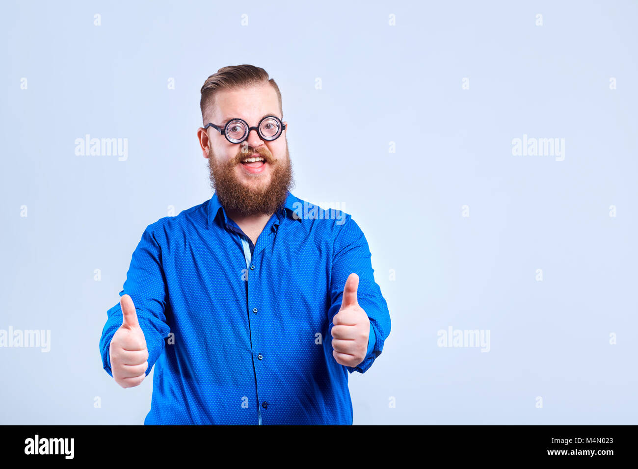 A fat, bearded man with glasses on a gray background with a posi Stock Photo