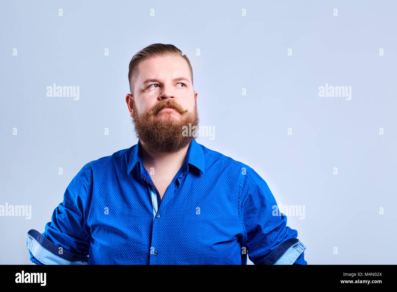 A fat, bearded man looks with a serious expression of emotion. Stock Photo