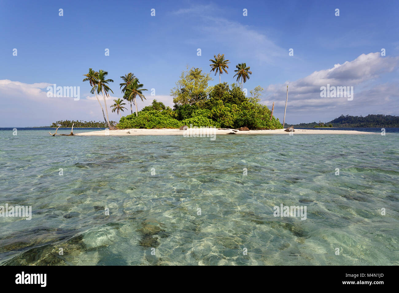 Small tropical island on horizon in beautiful tropical turquoise blue waters. Stock Photo