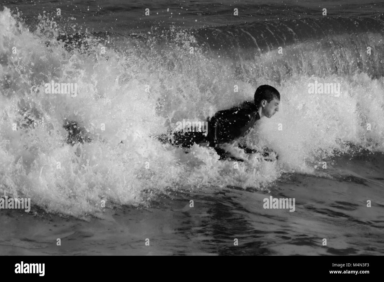 Dramatic Black and White Photo of a Daring Male Bodyboarder Surfing the Cold North Sea Waves at Aberdeen Beach, Scotland, UK. Winter 2018. Stock Photo