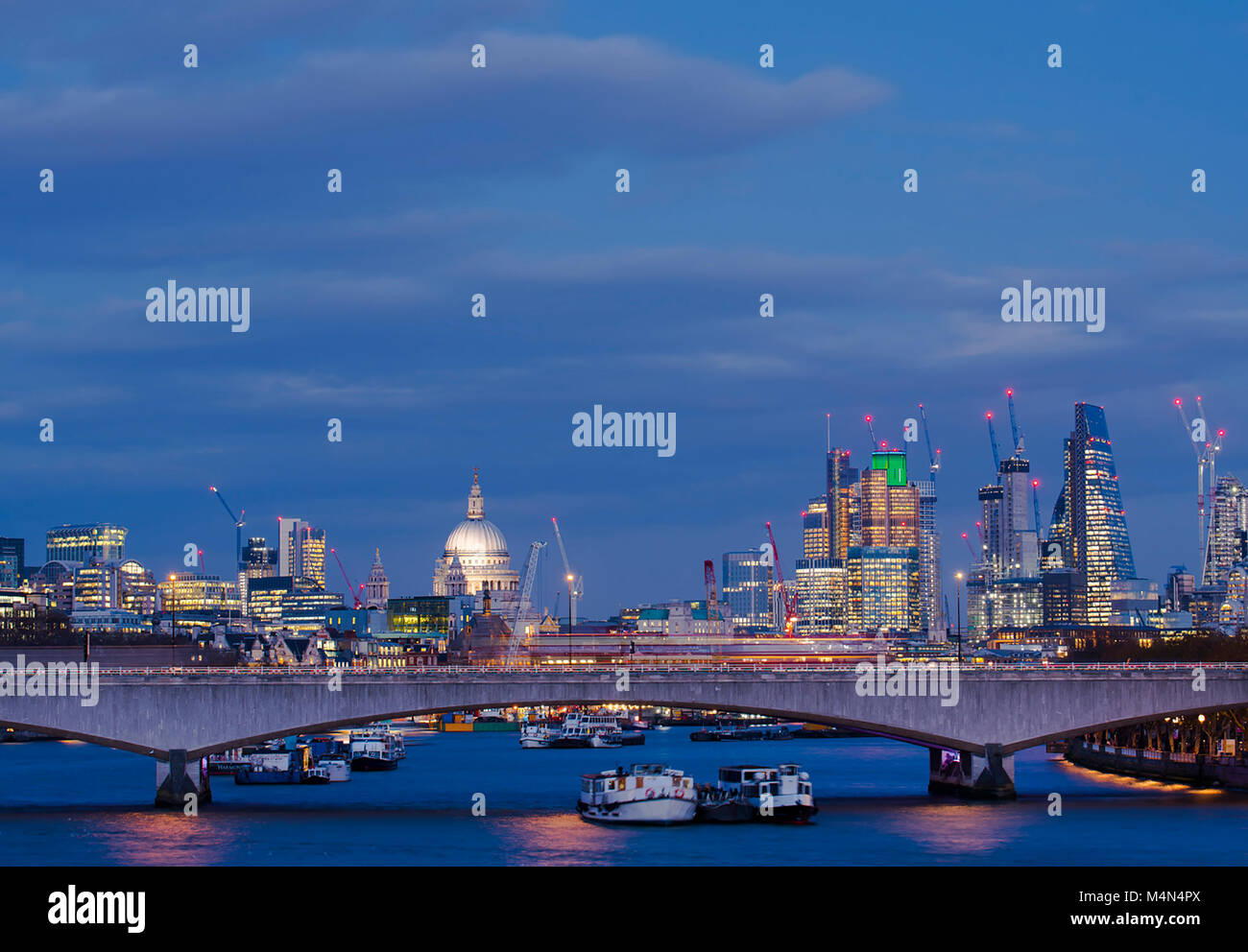 The City of London and St Pauls Cathedral from the Jubilee Bridge as the buildings become illuminated at dusk. Stock Photo