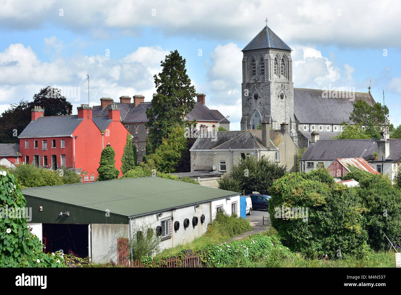 Old stone church of Saint Coca behind mostly industrial buildings in small Irish town of Kilcock in 2017. Stock Photo