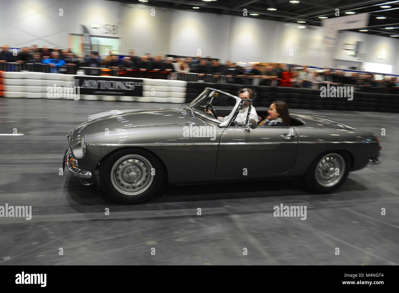 London, UK. 17th Feb, 2018. A MGB Abingdon Edition being driven in the daily promenade on the Grand Parade at the London Classic Car Show which is taking place at ExCel London, United Kingdom.  More than 700 of the world's finest classic cars are on display at the show ranging from vintage pre-war tourers to a modern concept cars. The show brings in around 37,000 visitors, ranging from serious petrol heads to people who just love beautiful and classic vehicles. Credit: Michael Preston/Alamy Live News Stock Photo