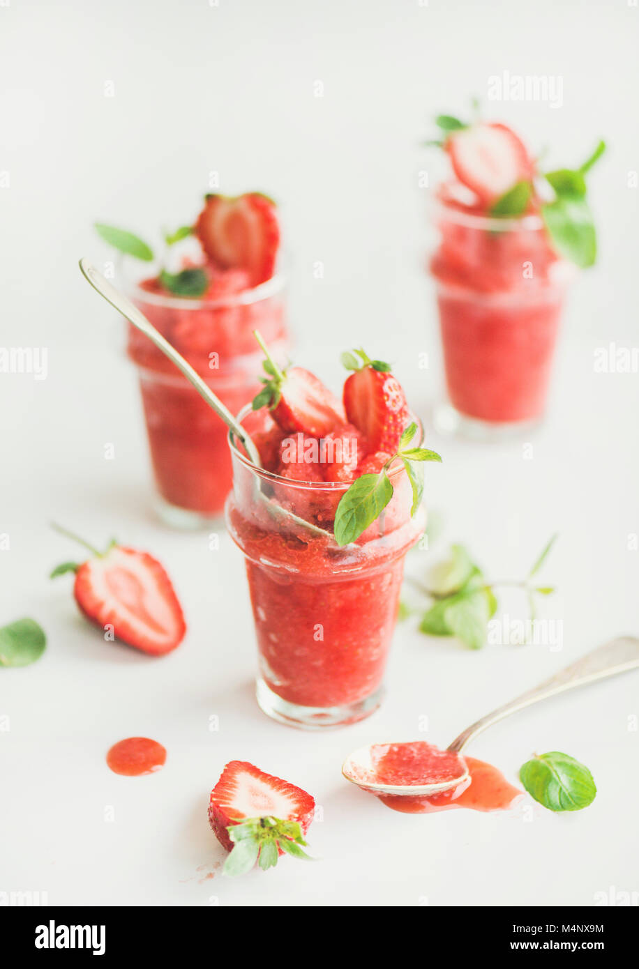 Healthy low calorie summer treat. Strawberry and champaigne granita, slushie or shaved ice dessert in glasses with mint, white background. Clean eatin Stock Photo