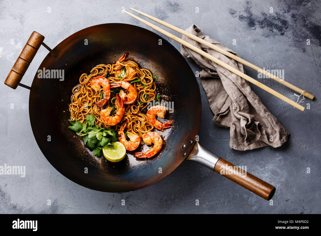 Ramen stirfry noodles with shrimp in wok pan on gray concrete