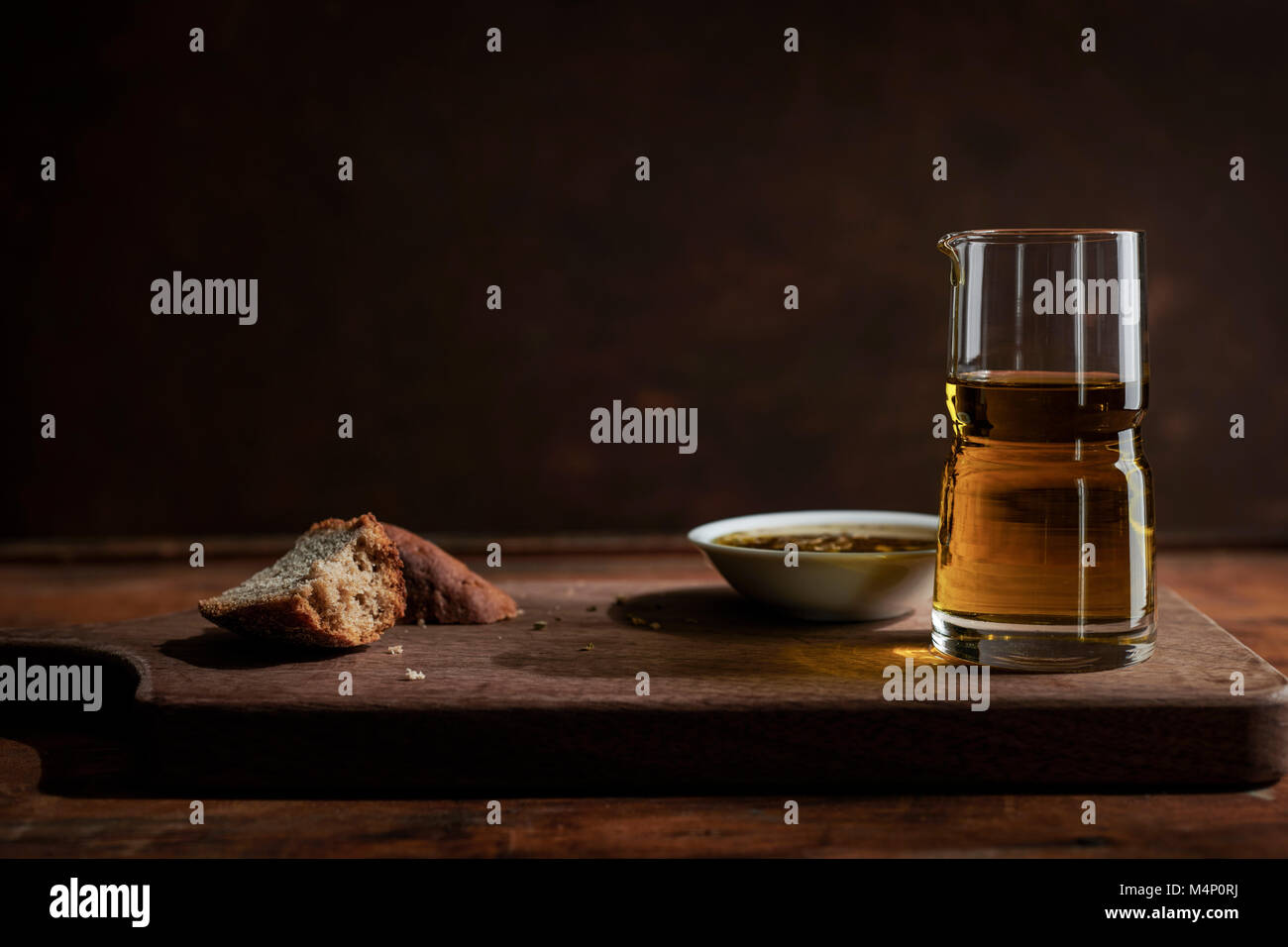 Broken chunks of rustic, rye bread with dipping oil bowl and glass on a ...