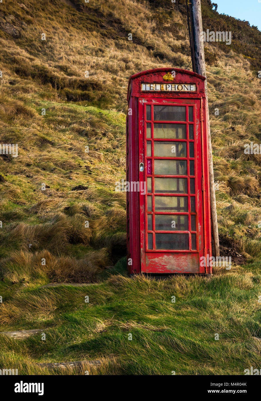 Old neglected Brisith red telephone box, still in working order in small seaside village, Crovie, Aberdeenshire, Scotland, UK Stock Photo