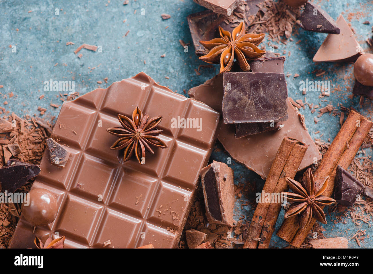 Chocolate pieces with spices and scattered cocoa on a stone background. Confectionery food photography. Dessert ingredients close-up. Stock Photo