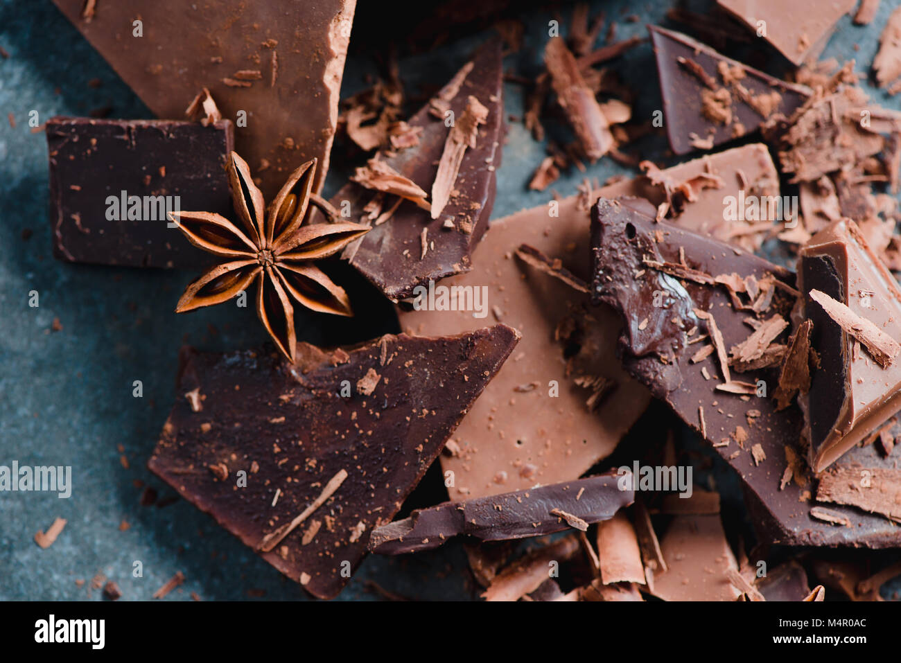 Chocolate pieces with spices and scattered cocoa on a stone background. Confectionery food photography. Dessert ingredients close-up. Stock Photo