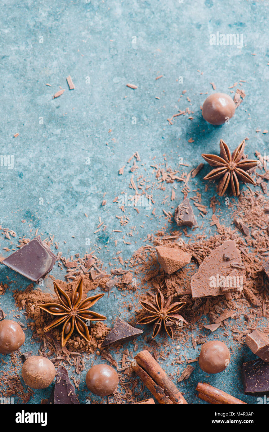 Dessert ingredients flat lay. Chunks of milk and bitter chocolate, spices and scattered cocoa on a stone background. Confectionery food photography. Stock Photo
