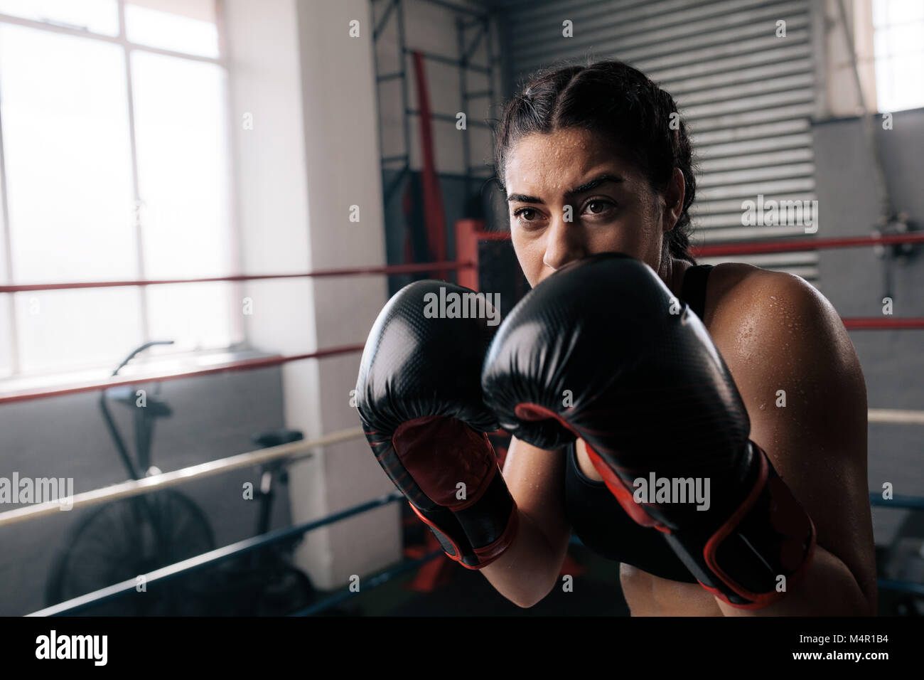 Boxer practicing her punches at a boxing studio. Close up of a female boxer doing shadow boxing inside a boxing ring. Stock Photo