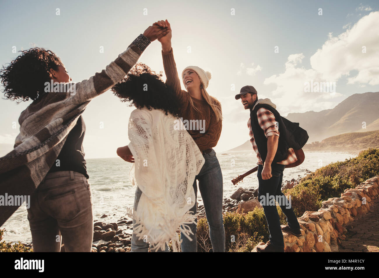 Friends on holiday smiling and enjoying outdoors. Group of man and women standing a embankment along the roadside. Stock Photo