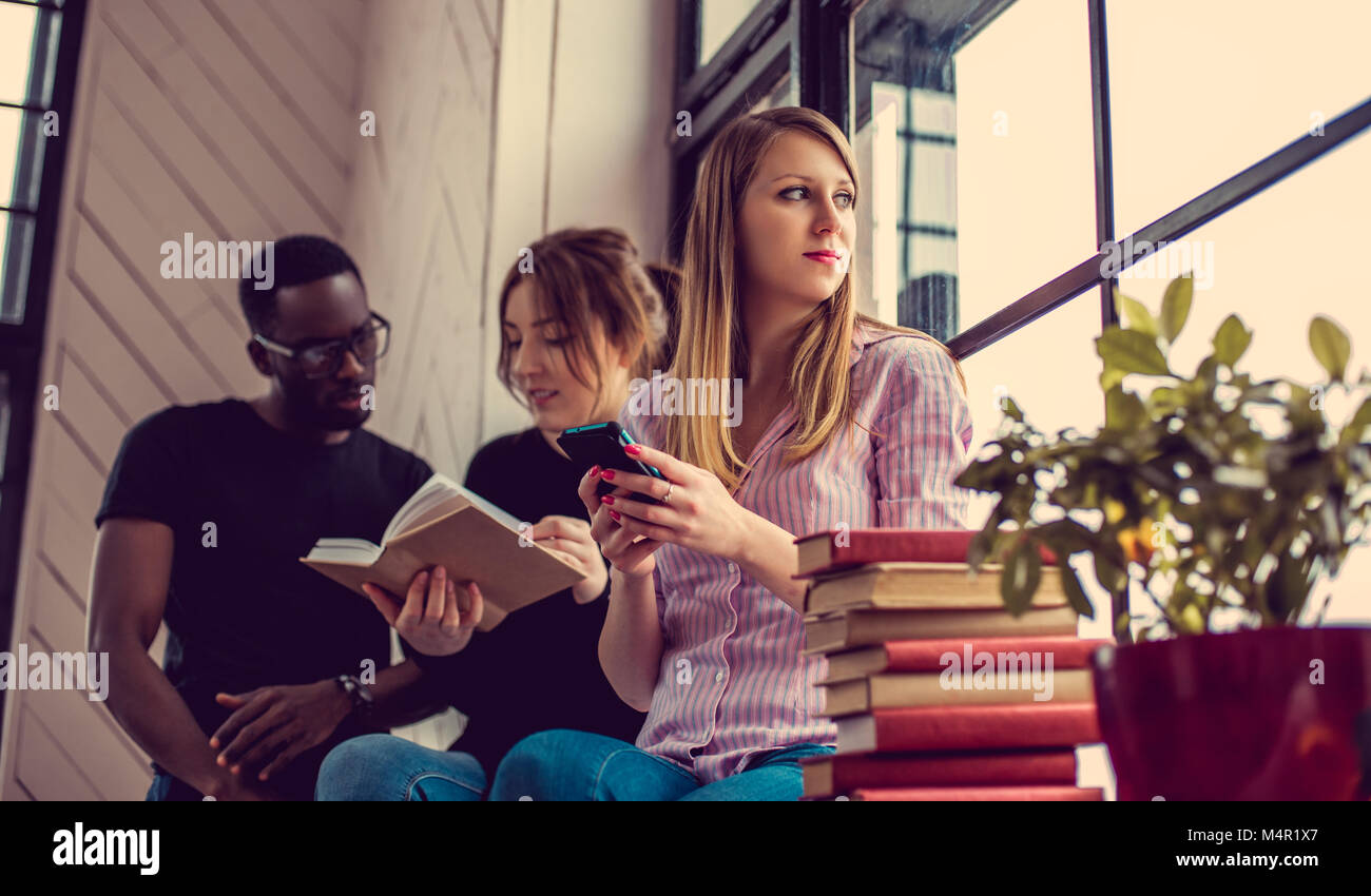 African american male and two caucasian females reading a book near ...
