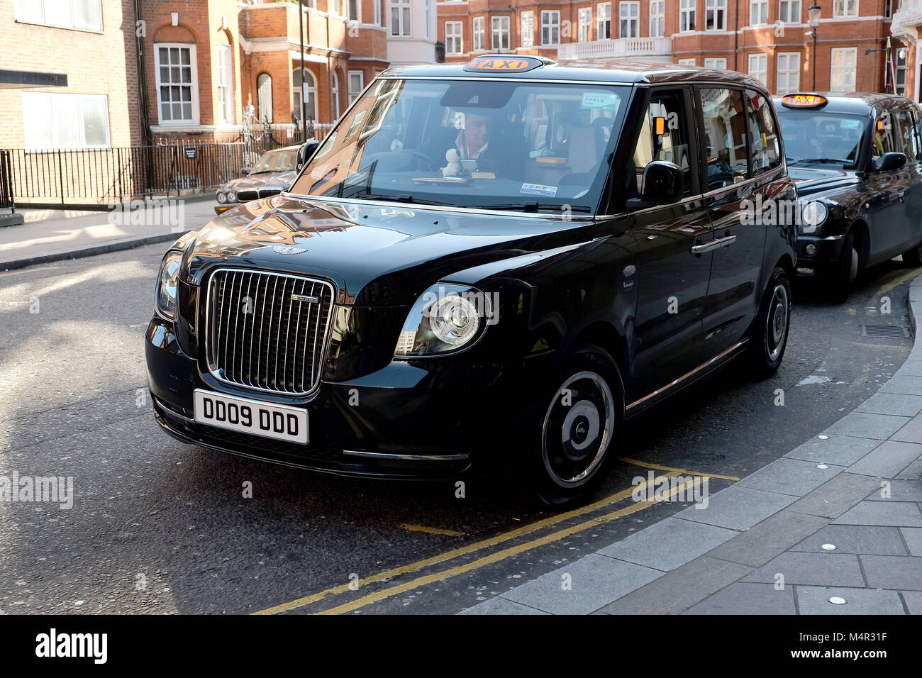 London's black cab has gone green as a new electric taxi waits outside Harrods in Knightsbridge to take passengers on the capital's roads. Stock Photo