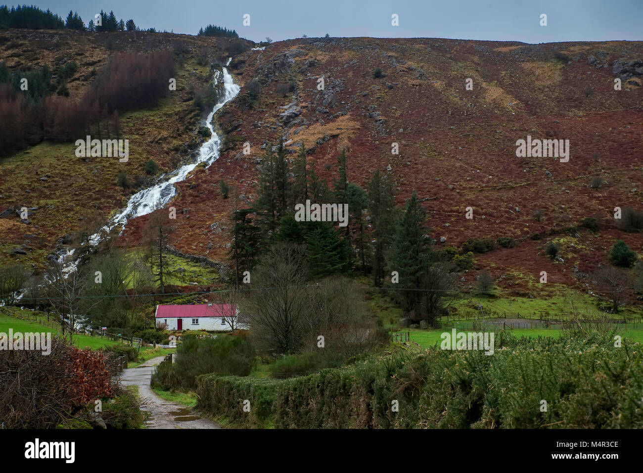 Red Roofed Cottage at the base of a Waterfall in Glenmalure co wicklow Stock Photo