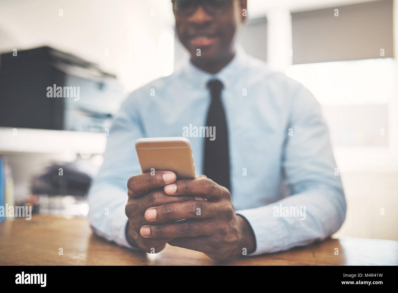 Smiling African entrepreneur sitting at a desk in his home office ...